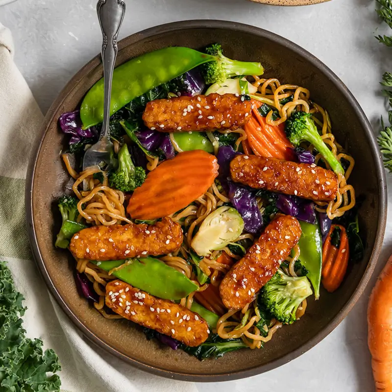 Tempeh teriyaki stir-fry with colorful vegetables and a glossy sauce in a bowl.