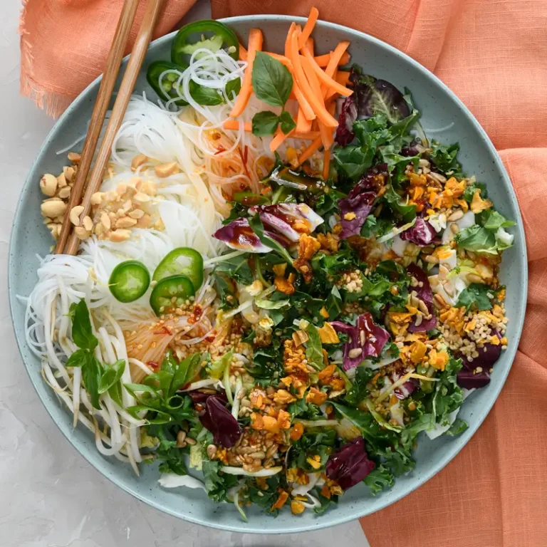 Vermicelli noodle bowl topped with Thai chili mango salad, showcasing fresh ingredients and vibrant colors.