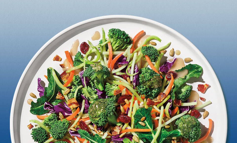 Chopped broccoli salad kit featuring fresh ingredients and vibrant vegetables in a clear bowl.