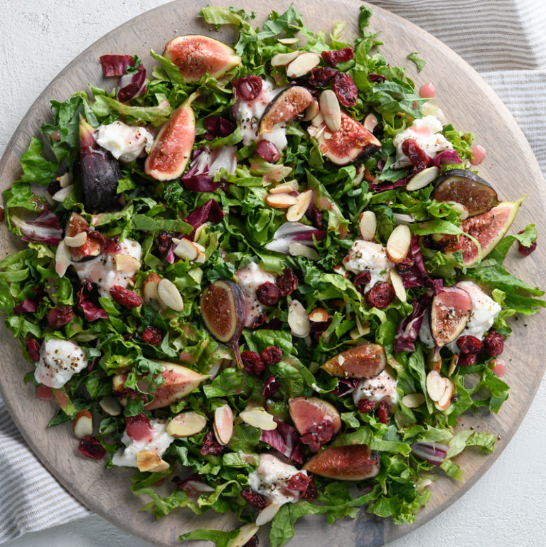Fig, burrata, and strawberry salad garnished with rose petals, showcasing vibrant colors and fresh ingredients.