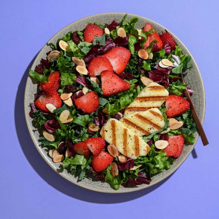 Grilled halloumi cheese and strawberry rose salad garnished with fresh greens and vibrant colors.