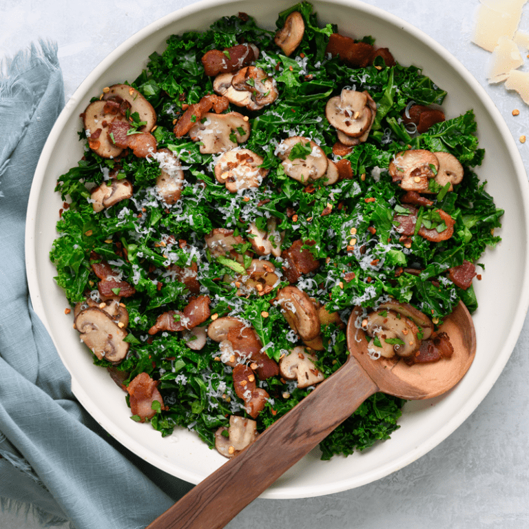 Kale sauté with mushrooms and crispy bacon served in a skillet, showcasing a delicious, healthy dish.