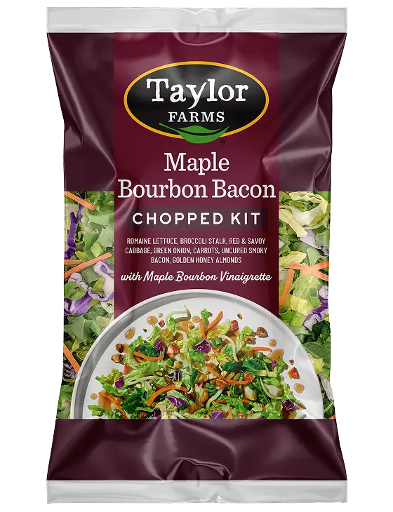 Maple bourbon dressing bottle with fresh salad ingredients in the background.