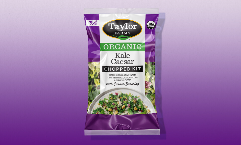 Organic Kale Caesar Chopped Salad Kit featuring fresh greens and creamy dressing in a vibrant packaging design.