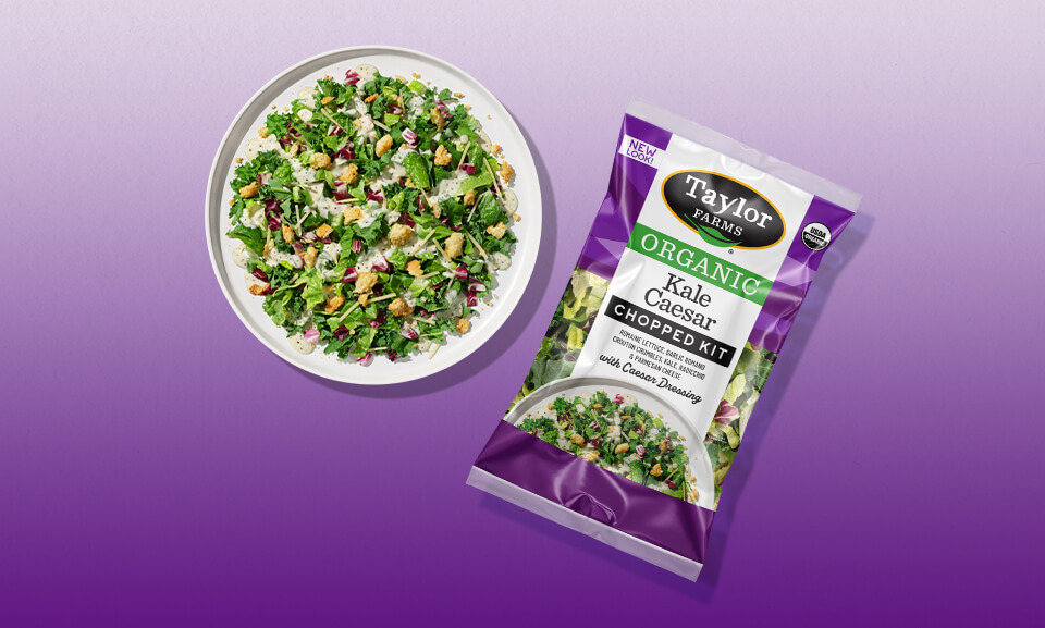 Organic Kale Caesar Chopped Kit displayed on a plate, featuring fresh greens, parmesan, and dressing.