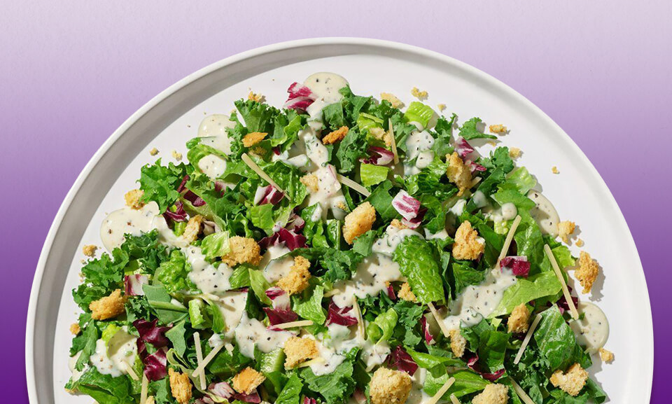 Organic Kale Caesar Chopped Salad Kit with croutons and dressing, showcasing fresh ingredients and vibrant colors.