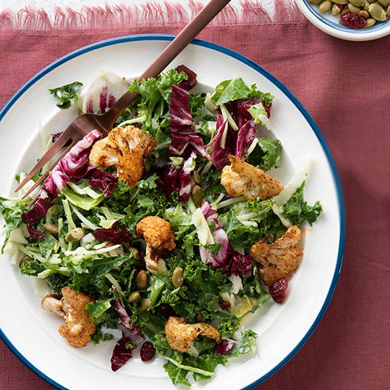 Sweet kale and cauliflower salad featuring vibrant greens, crunchy textures, and a healthy, nutritious mix.