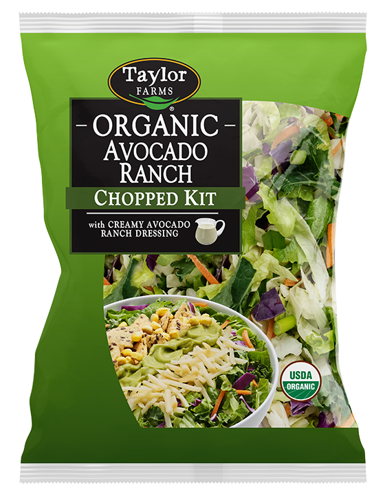 The Organic Avocado Ranch Chopped Salad kit package, showing chopped romaine lettuce, cabbage, kale, and carrots topped with smoked white cheddar, corn flax chips, and crispy corn.