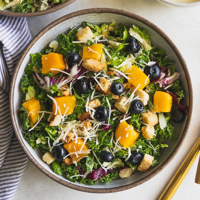 Mango Asiago Kale salad featuring vibrant greens, diced mango, and Asiago cheese.