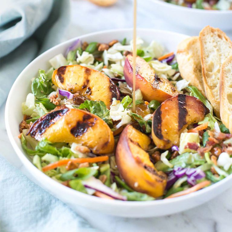 Fresh peach salad with vibrant vegetables, nuts, and a light dressing, perfect for summer meals.