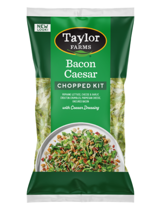 The Bacon Caesar Chopped Salad kit package, showing chopped romaine lettuce topped with cheese garlic crouton crumbles, Parmesan cheese, bacon, and tangy Caesar dressing.