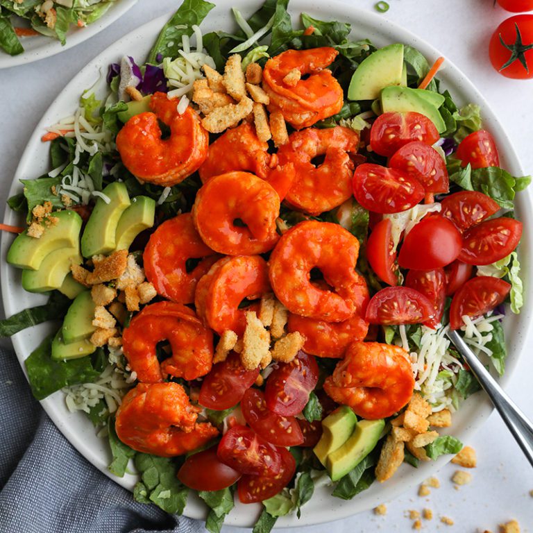 Fresh Taylor Farms salad featuring colorful mixed greens, cherry tomatoes, and sliced cucumbers in a bowl.