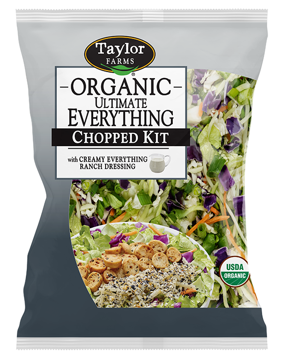 The Organic Ultimate Everything Chopped Salad kit package, showing green romaine lettuce, red cabbage, shredded broccoli, and carrots topped with smoked white cheddar, bagel chips, and Everything Ranch dressing.