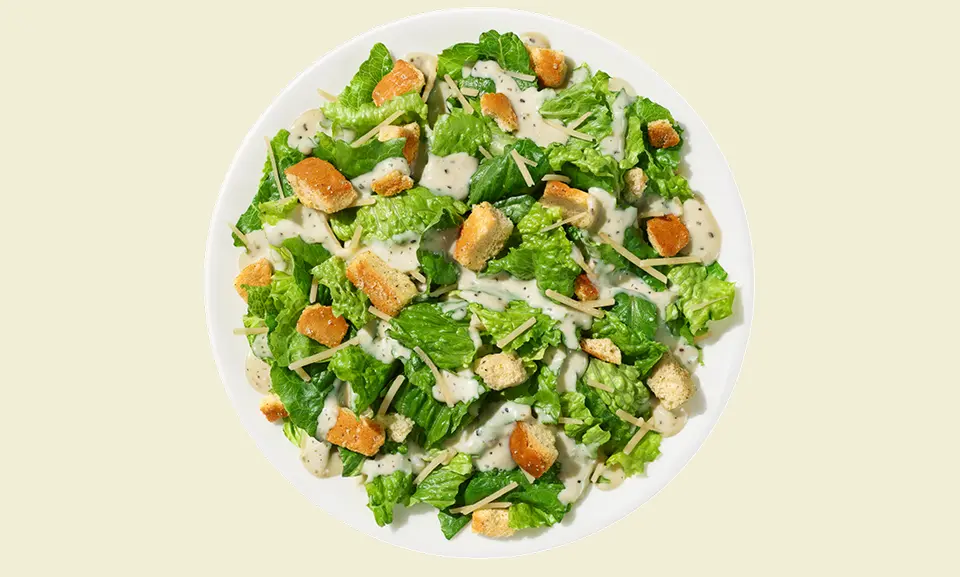 Fresh Caesar salad kit served on a plate with crisp lettuce, croutons, and Parmesan cheese.