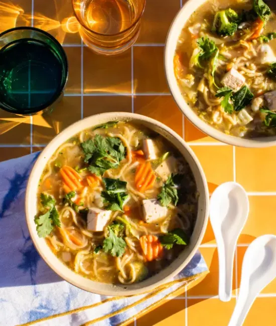 two ginger soy soups in bowls on a yellow tiled table