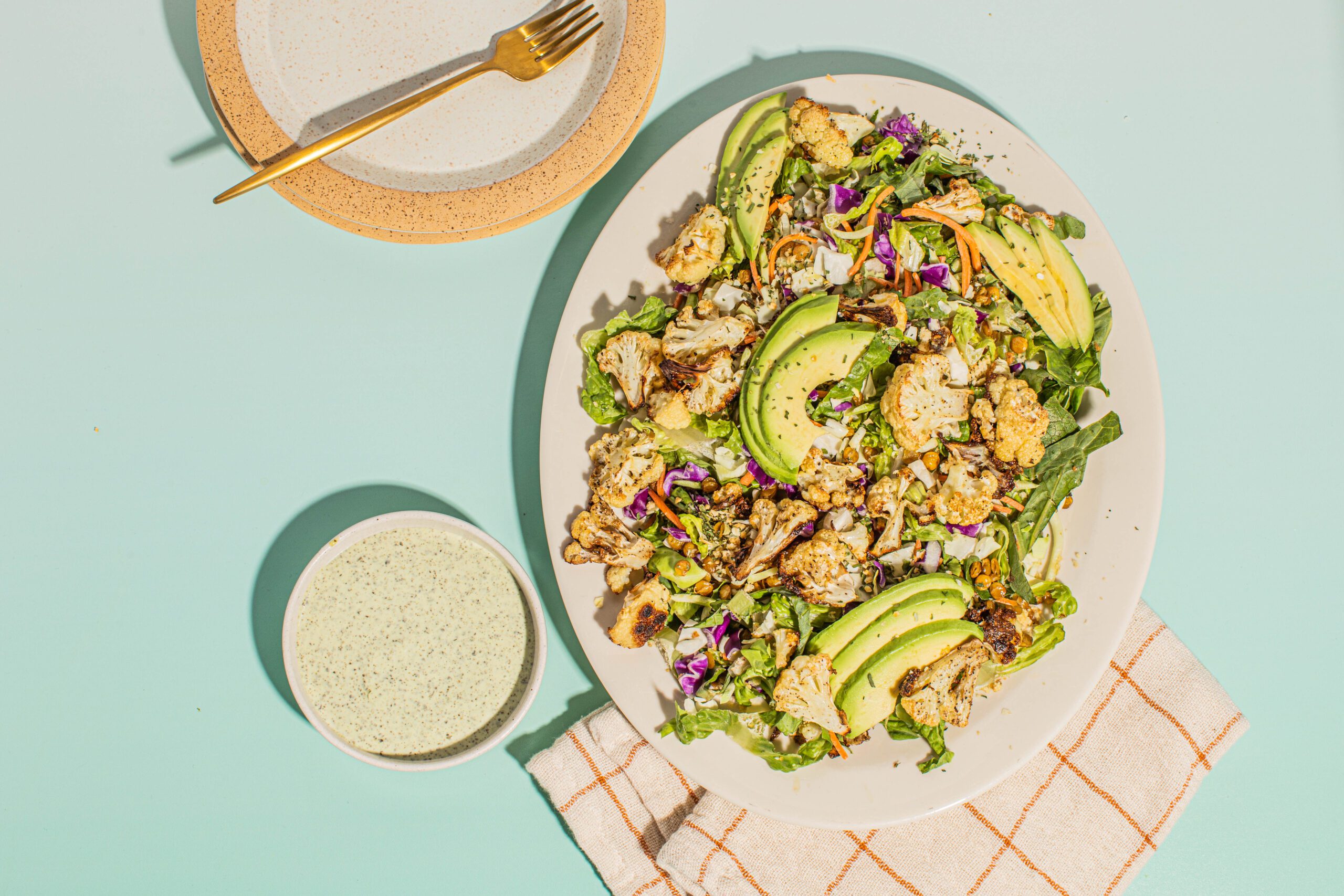 Roasted Cauliflower Green Goddess Salad on a plate with a side of dressing and a fork