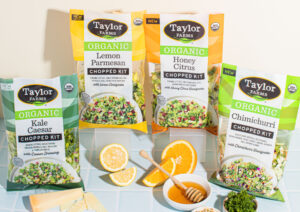 Taylor Farms organic chopped salad kits in packages with fruit, honey, cheese, and herbs