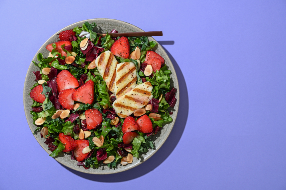 Taylor Farms Grilled Halloumi and Strawberry Rose Salad on a plate with a purple background