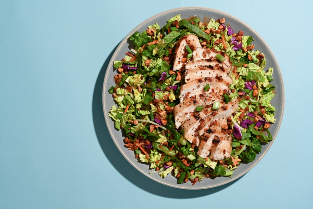 Taylor Farms Maple Bourbon Grilled Chicken Salad on a plate with a blue background