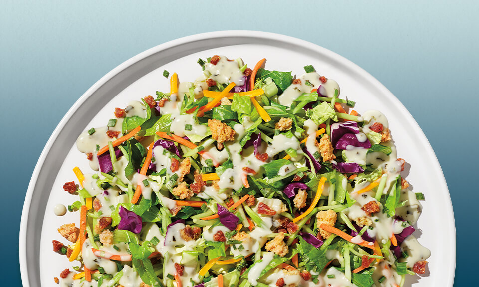 Chopped salad kit featuring cheddar ranch dressing, fresh greens, and colorful vegetables.