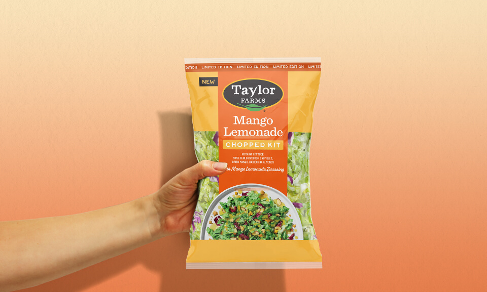 Person holding a bag of Mango Lemonade Chopped Salad Kit from Taylor Farms.