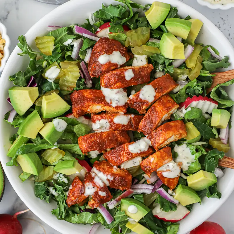 Nashville hot chicken tender salad topped with fresh greens and drizzled in creamy dressing.