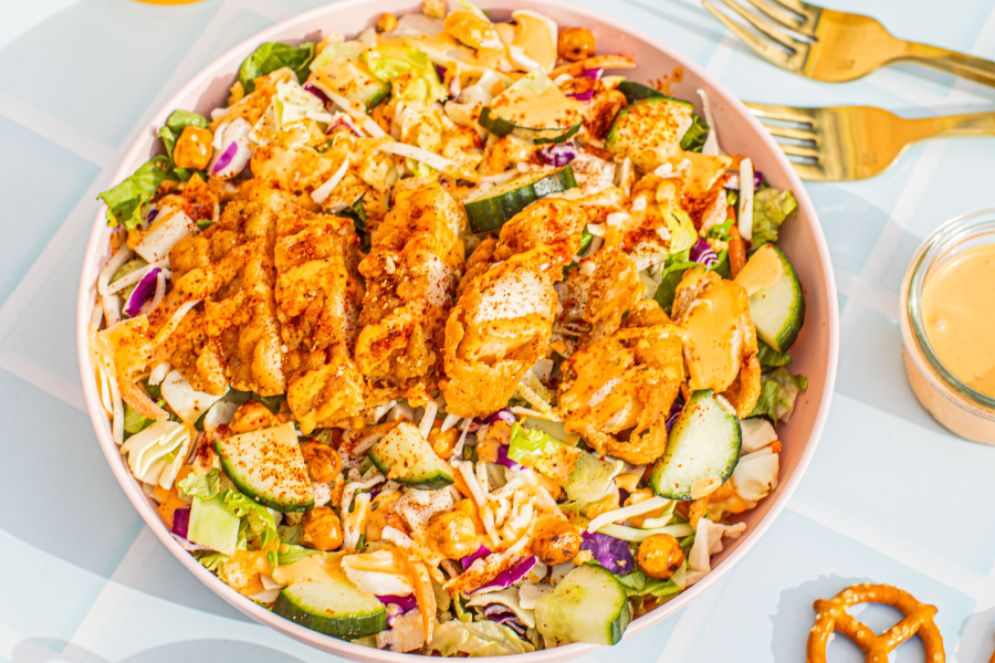 Taylor Farms Kickin’ Chicken Buffalo Salad in a bowl next to two forks