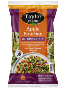 The Taylor Farms Apple Bourbon Chopped Salad Kit package, showing romaine lettuce, diced apples, pieces of smoked gouda, shredded carrots, red cabbage, pieces of uncured smoky bacon, golden honey almonds, and maple bourbon vinaigrette.