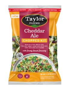 The Taylor Farms Cheddar Ale Chopped Salad Kit package, showing green leaf lettuce, broccoli stalks, red and savoy cabbage, cheddar cheese pretzel bits, carrots, green onion, ale seasoning, and smokey ranch dressing.