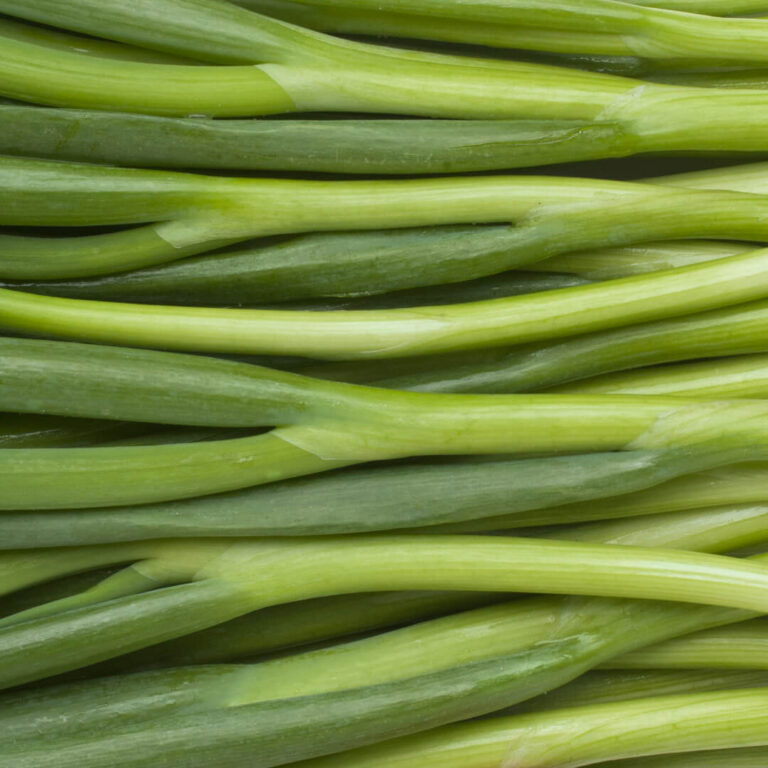 Fresh green onions arranged neatly on a wooden cutting board, highlighting their vibrant color and crisp texture.