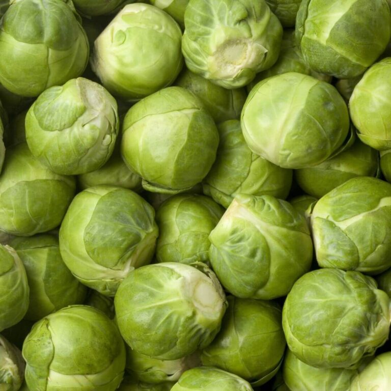 Fresh, vibrant Brussels sprouts arranged on a wooden cutting board.