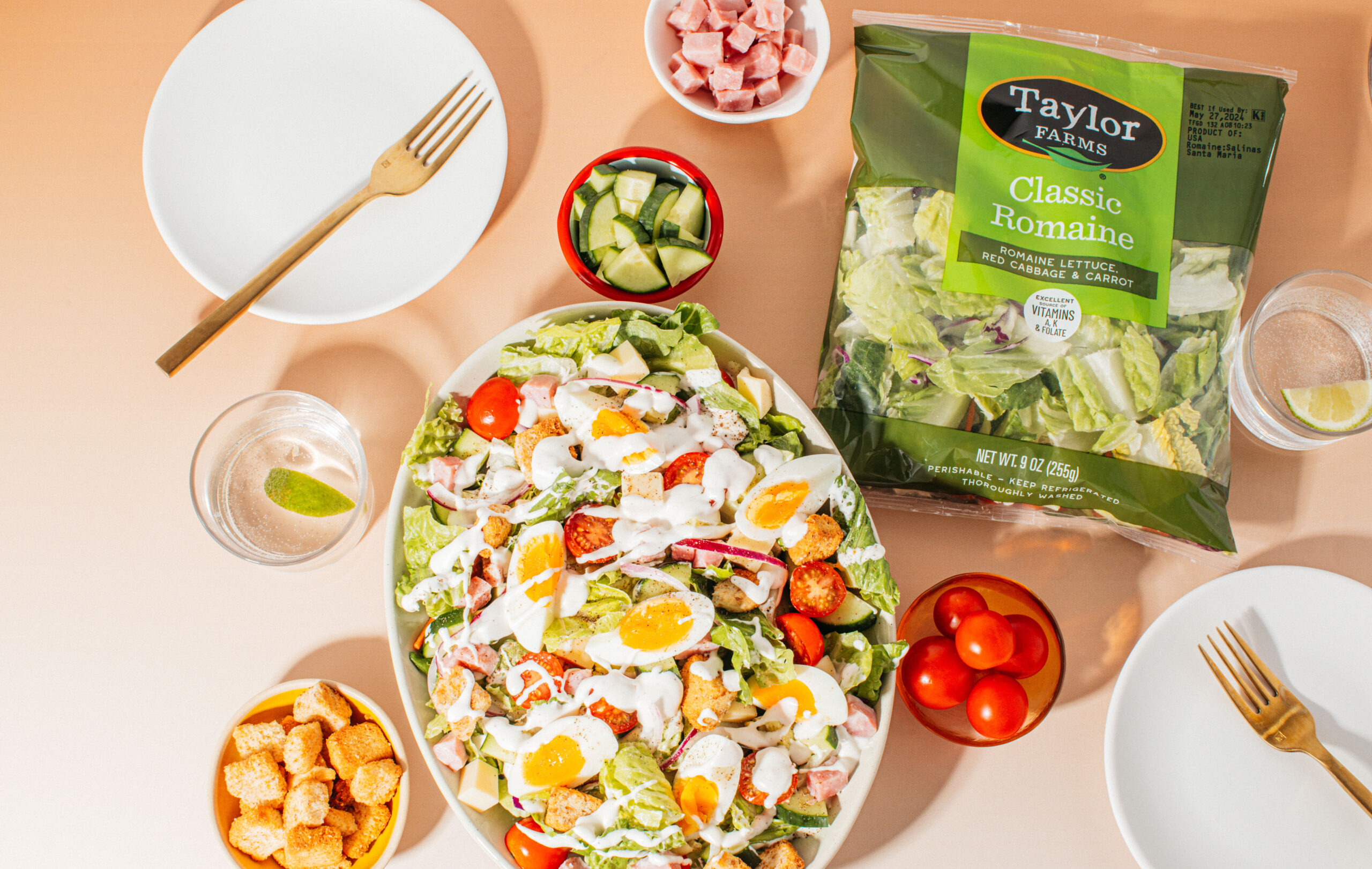 Fresh summer salad bowl featuring mixed greens, cherry tomatoes, cucumbers, and sliced carrots from Taylor Farms.