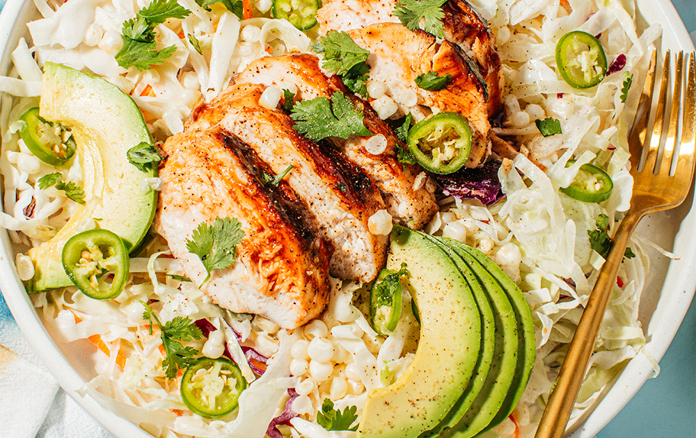 Grilled BBQ chicken served with fresh vegetables on a rustic wooden table, perfect for summer cookouts.