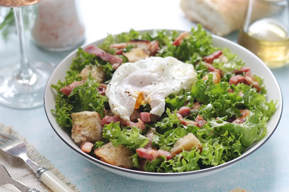 Fresh Lyonnaise salad featuring crispy lettuce, bacon, poached egg, and tangy vinaigrette from Taylor Farms.