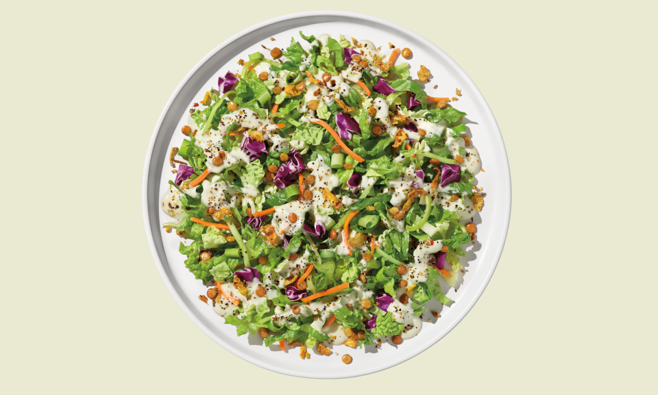 Wedge Chopped Salad Kit with fresh greens, tomatoes, and dressing on a wooden background.
